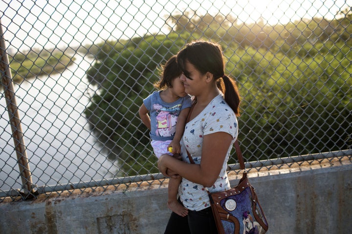 A Honduran woman holds her 2-year-old daughter as they wait on the Mexican side of the international bridge at Brownsville, Texas, on June 28.