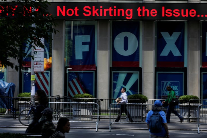 People pass by ads for Fox News at the News Corporation building in New York City in June. 