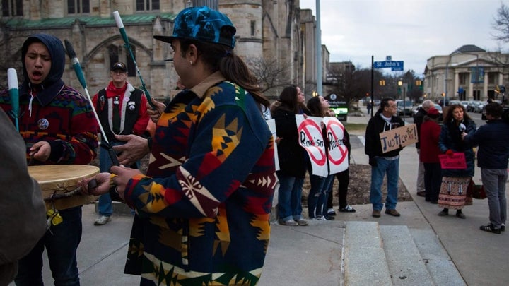 A group of men sing and drum on the steps of Kalamazoo City Hall in March, before the city commission voted to remove the Fountain of the Pioneers. More cities are contending with calls to remove statues depicting stereotyped and subjugated Native Americans.