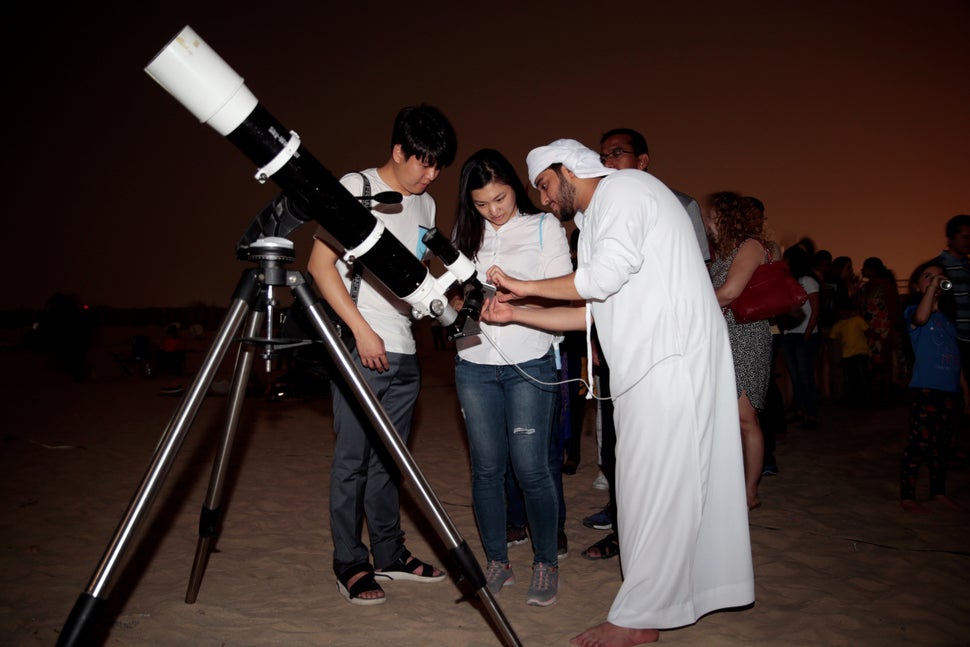 An Emirati man uses a telescope to take a picture of the lunar eclipse of a full