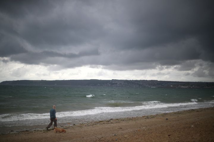 A woman walks her dog as storm clouds gather near Penzance in Cornwall late on Friday.