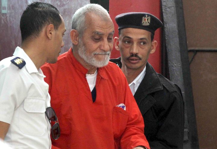 Mohamed Badie, top leader of Egypt's outlawed Muslim Brotherhood, is led by police to talk during a trial hearing in Cairo in 2015