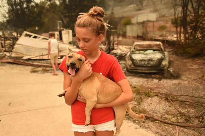 Kambryn Brilz, 12, holds her dog Zoe in front of what remains of her burnt home after she was returned safely by a neighbor during the Carr fire in Redding, California, on July 27.