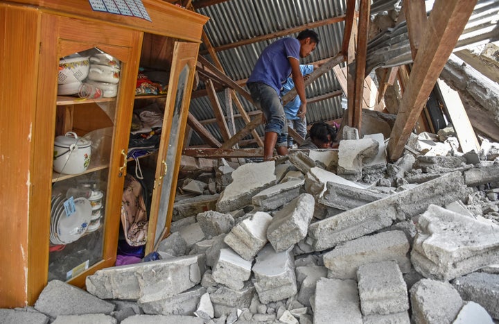 A villager walks through the ruins of a collapsed house following the earthquake at the Sembalun Selong village in Lombo