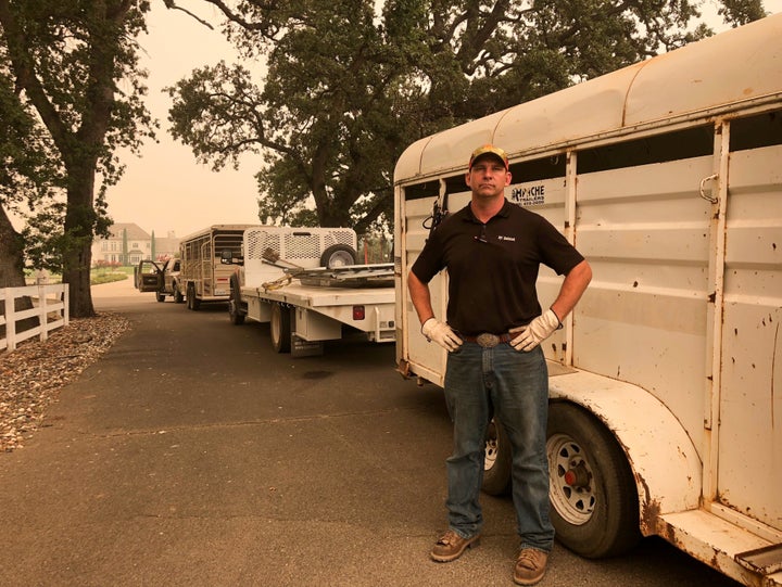 Tucker Zimmerman stands next to the trailer he has used to rescue scores of horses left behind in evacuated areas from a wildfire in Shasta County, west of Redding, California.