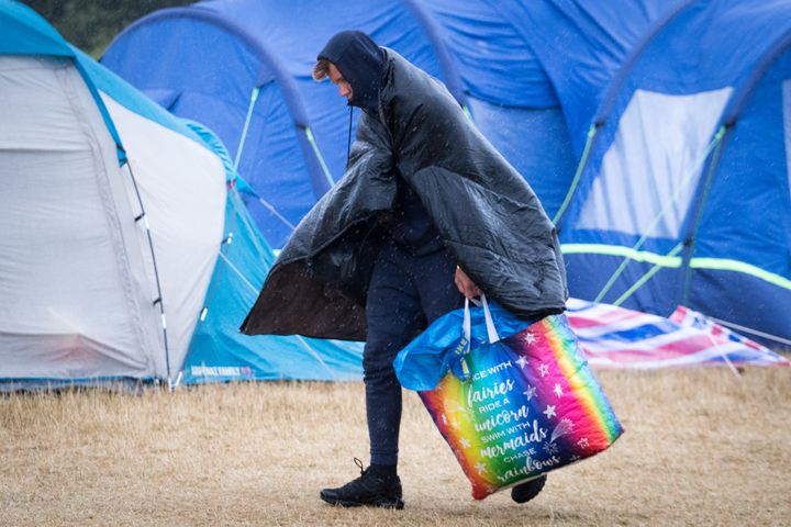 A festival goer walks in the wind and rain at Camp Bestival, at Lulworth Castle, on Sunday.