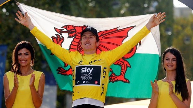 Cycling - Tour de France - The 116-km Stage 21 from Houilles to Paris Champs-Elysees - July 29, 2018 - Team Sky rider Geraint Thomas of Britain celebrates his overall victory on the podium with a Welsh flag. REUTERS/Philippe Wojazer