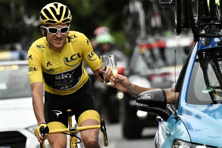 Thomas drinks champagne with Great Britain Team Sky team principal, Sir Dave Brailsford, who rides in a car.