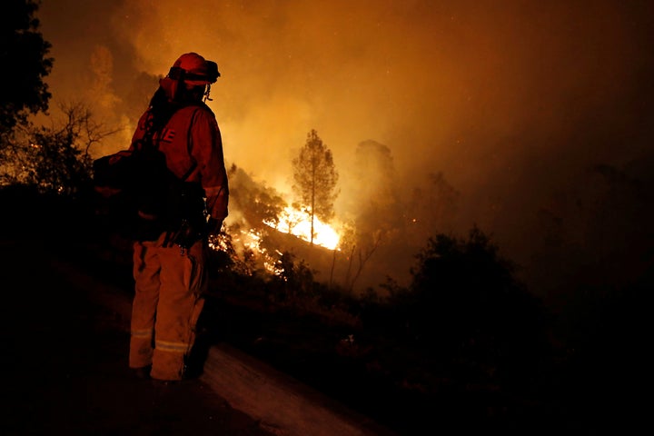 A firefighter watches flames advance up a hill towards homes as crews battle the Carr Fire, west of Redding, California.