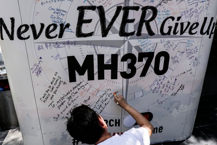 A man writes a message on a board on the first anniversary of the missing Malaysian Airlines MH370