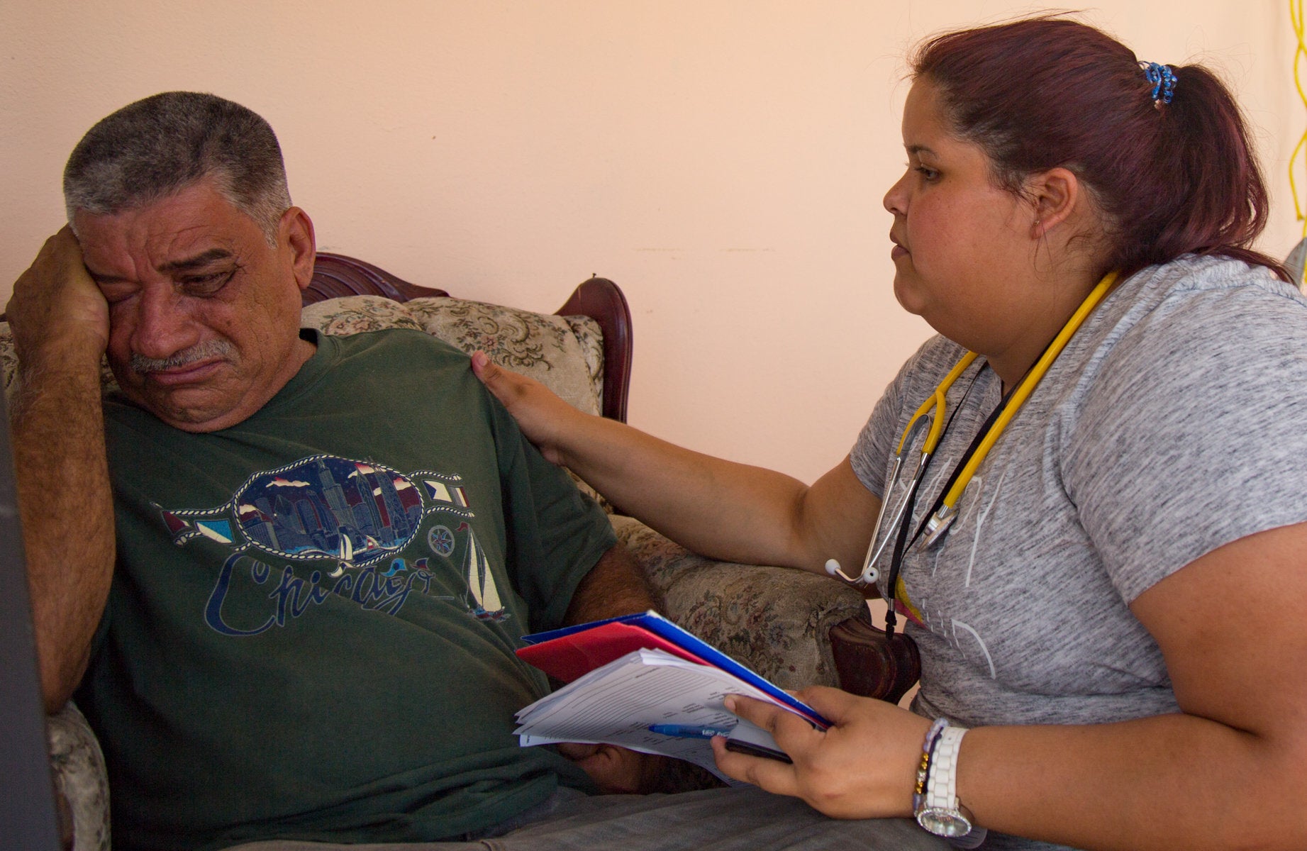Cristina, a nurse for the Iniciativa Comunitaria health brigade, does a check up on Luis Cortez in front of his home in Aguad