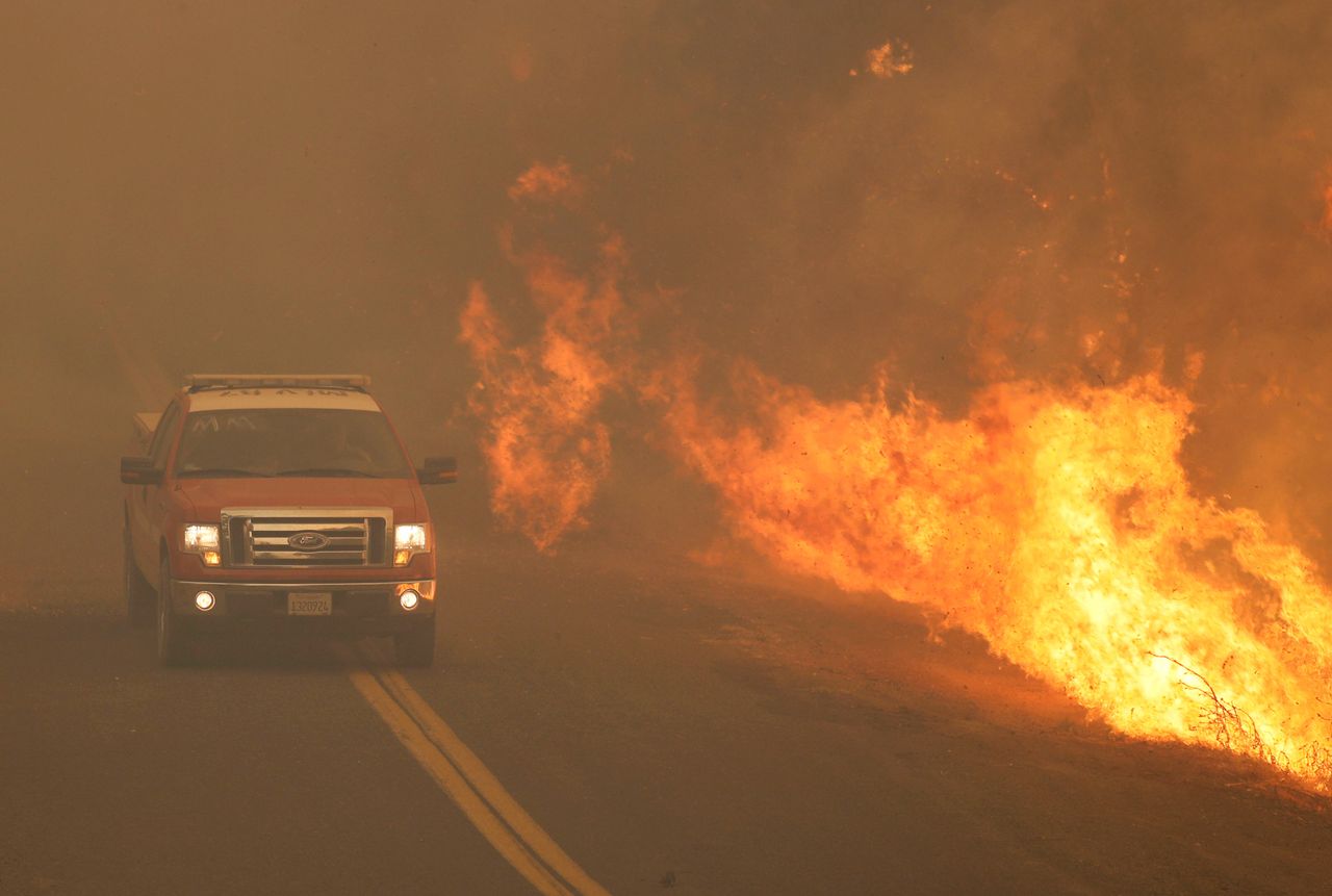 A fire truck rushes past flames that overran a road at the River Fire in Lakeport, California on Tuesday.