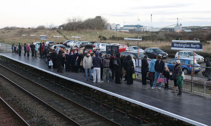 Rail passengers wait for a train at the temporary Workington North railway station which has been built in six days to reunite the Cumbrian town that was split in two after several bridges in the area were lost after torrential rain just over a week ago.