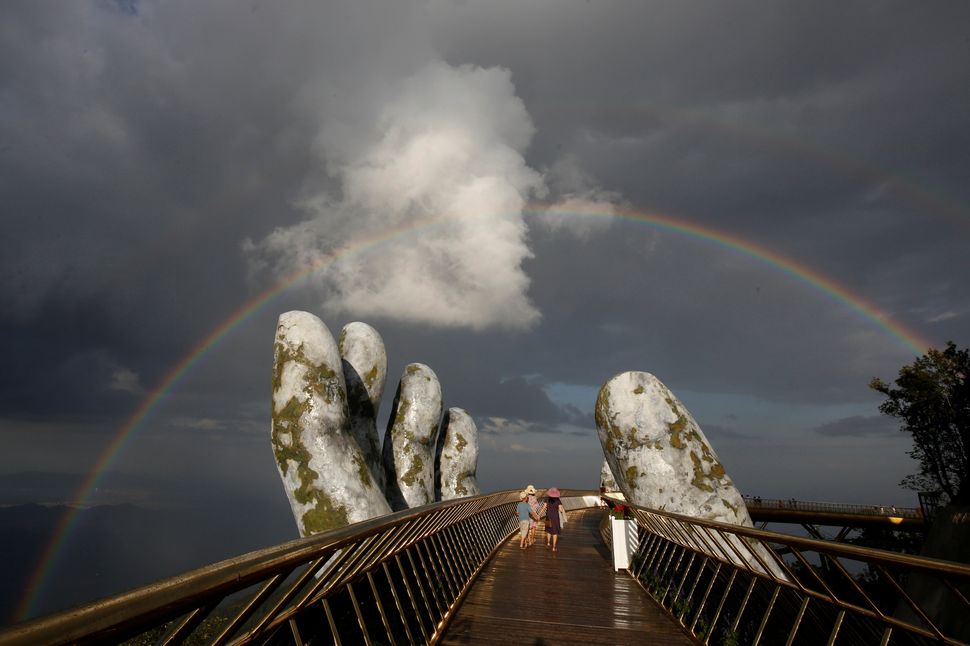 A double rainbow appears above the giant hands structure.