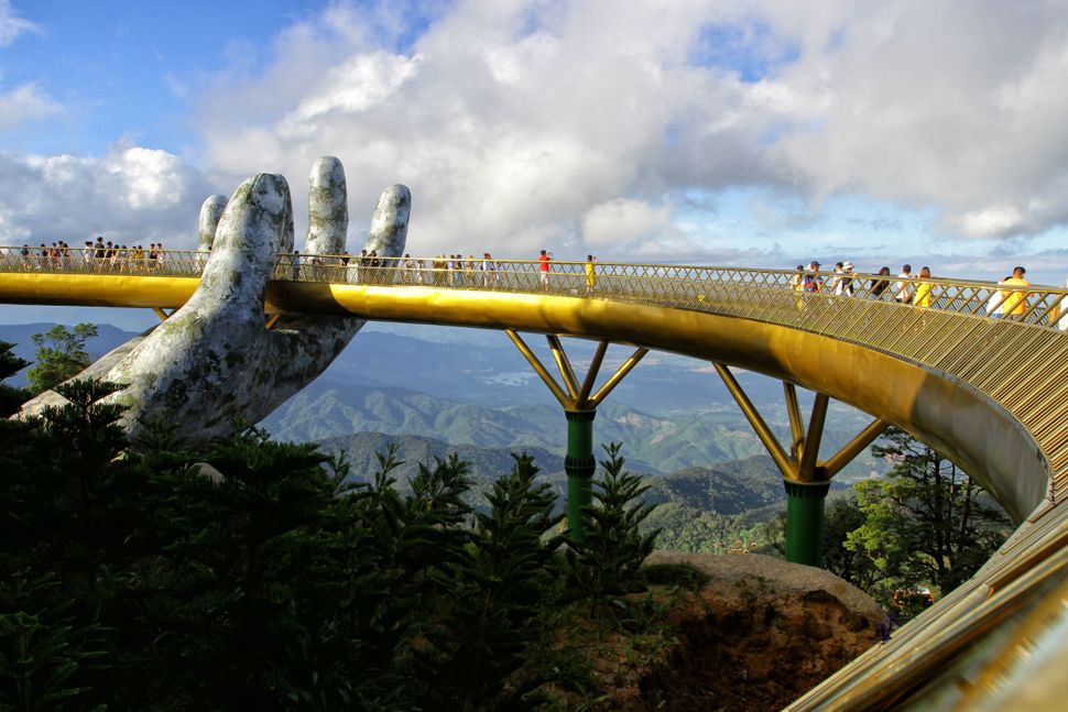 In this photograph taken on July 31, 2018, visitors walk along the 150-meter long Cau Vang "Golden Bridge" in the Ba Na Hills