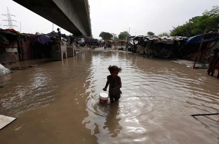 A girl carries drinking water as she wades through a flooded street after a rise in the waters of the Yamuna River in New Delhi on July 31.