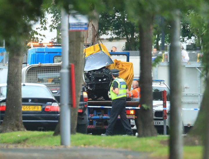 A car covered by a tarpaulin is removed from the scene on Bingley Road at the junction with Toller Lane in Bradford following a road traffic collision where four males died in a car which was being followed by an unmarked police vehicle when it crashed.