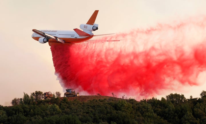 A DC-10 air tanker drops fire retardant along the crest of a hill to protect the two bulldozers below that were cutting fire lines near the River fire on Thursday.