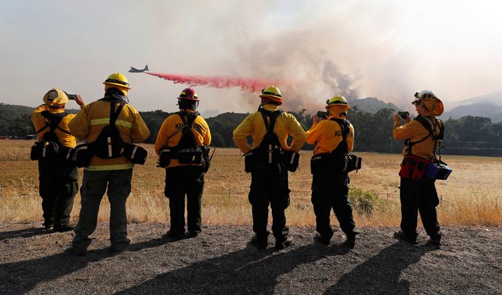 Firefighters watch as an air tanker drops fire retardant along the crest of a hill near Lakeport, California, on Aug. 2, 2018.