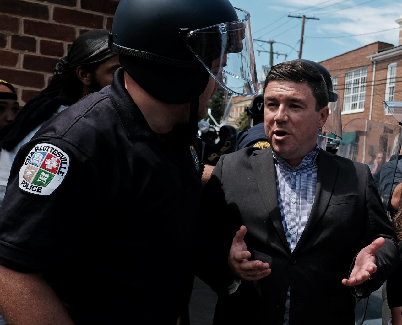 Unite The Right rally organizer Jason Kessler is escorted by police after he attempted to speak at a press conference in front of Charlottesville City Hall in Charlottesville, Virginia, August 13, 2017.