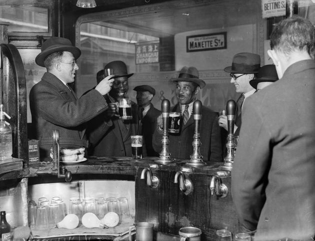 The original photograph of customers raising a glass inside the Pillars of Hercules pub in Soho in November 1933.