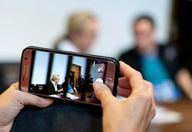 A woman takes a photo of a man in the dock of the court in Freiburg