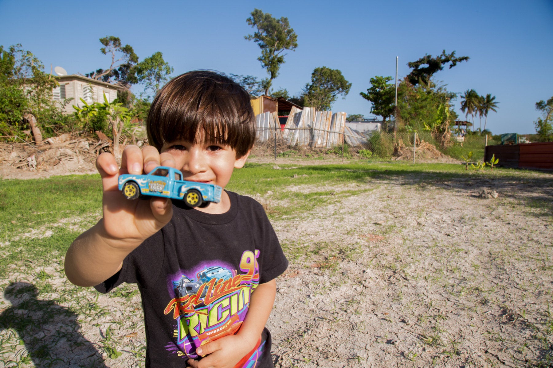 A 4-year old boy plays with his toy truck in the backyard of his home in Peñuelas. His house was flooded by coal ash f