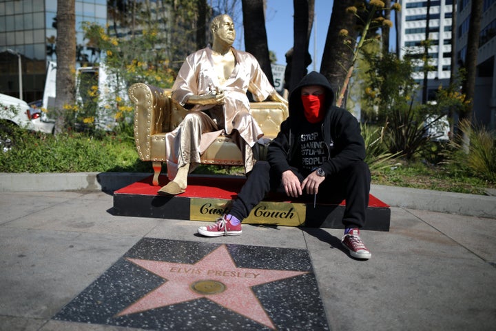 Artist Plastic Jesus sits on his statue of Harvey Weinstein on a casting couch on Hollywood Boulevard in Los Angeles.