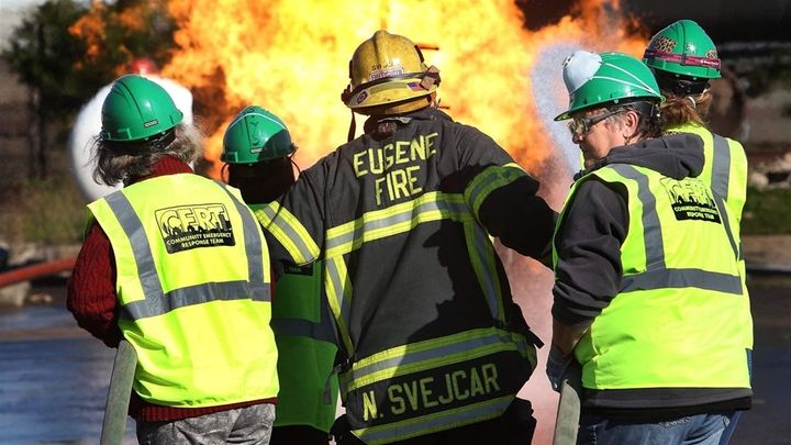 Firefighter Nathan Svejcar, center, leads a pair of two-person teams to knock down a fire during a Community Emergency Response Teams (CERT) training in Eugene, Oregon. Over the past 25 years, the number of CERT training programs has grown from a handful to about 2,800 nationwide. 