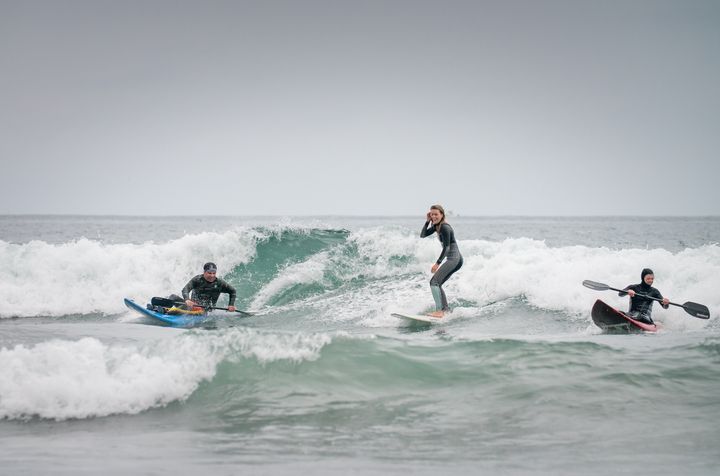 High Fives Athletes share a wave in San Clemente during an adaptive surf camp in 2017.