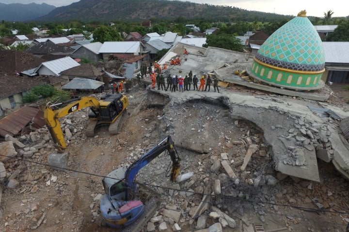 Rescue workers and soldiers search through the rubble for earthquake victims in Lombok, Indonesia.