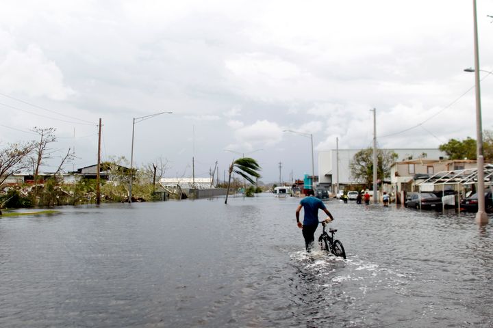 A man wades on the water while pushing his bicycle through a flooded street in the aftermath of Hurricane Maria in Catano, Puerto Rico on September 22, 2017.