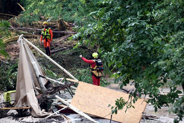 Rescuers stand in a flooded and damaged area of a camp site after storms and heavy rain led to mass evacuations in France