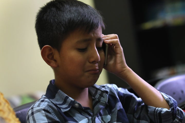 A 10-year-old child speaks with his mother on the phone after he was reunited with his father at the Nuestras Raices immigran