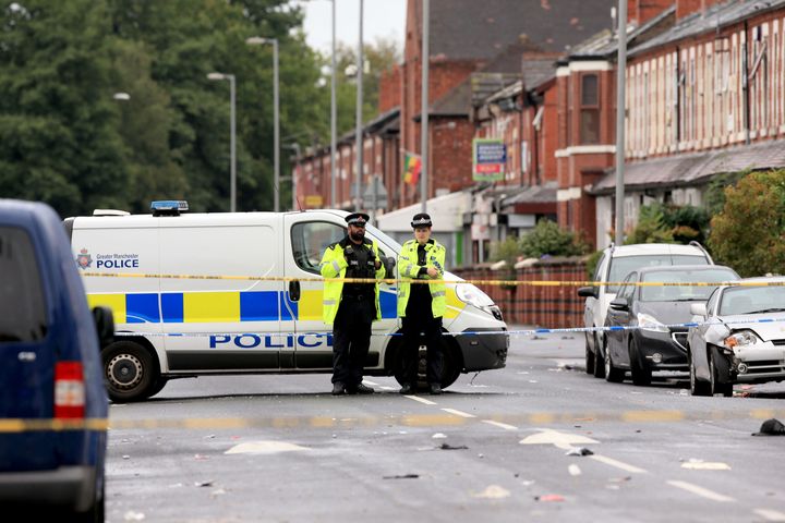 Police officers stand at the cordoned off area in Claremont Road, Moss Side, Manchester, where several people have been injured after a shooting.