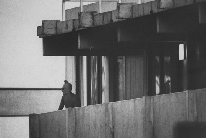 Stocking-masked Black September terrorist looking out as he guards the Israeli hostages