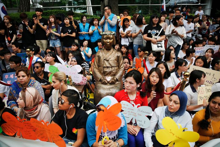 Demonstrators sit around a "comfort woman" statue during the weekly Wednesday protest demanding for an apology and compensation from the Japanese government in Seoul, South Korea, July 22, 2015.