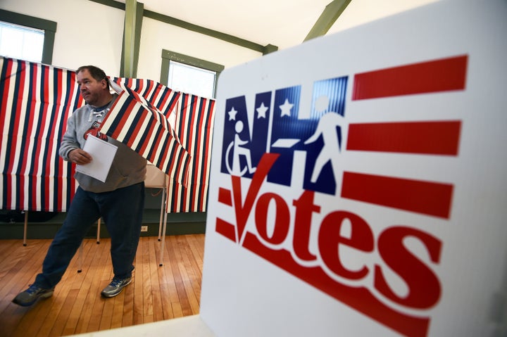 A man walks out of a voting booth holding his ballot in the 2016 presidential primary in Canterbury, New Hampshire.