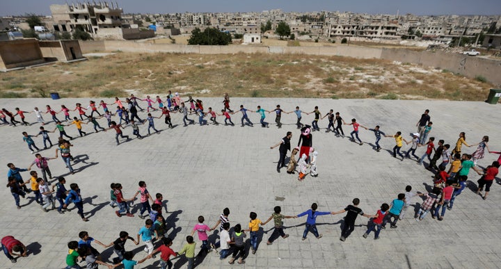 Students form a circle as they play during a celebration marking the end of the school year, at 'Syria, The Hope' school on the outskirts of the rebel-controlled area of Maaret al-Numan town, in Idlib province, Syria, on June 1, 2016. The school is partially occupied and it teaches students until fourth grade. The building that is heavily damaged was used by government forces as a base before the rebel fighters took control of the area.