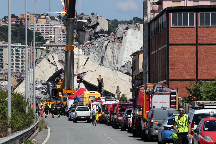Firefighters and rescue workers stand at the site of a collapsed Morandi Bridge in the port city of Genoa, Italy.