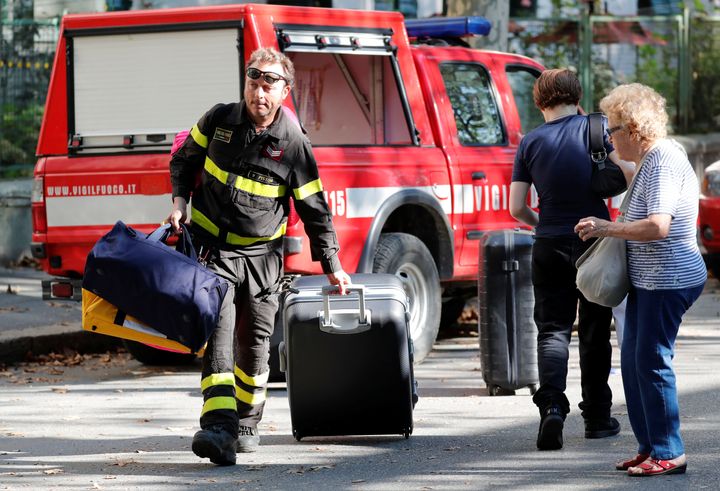 A firefighter carries personal belongings of a woman after she recovered them from her house following a Morandi Bridge collapse.