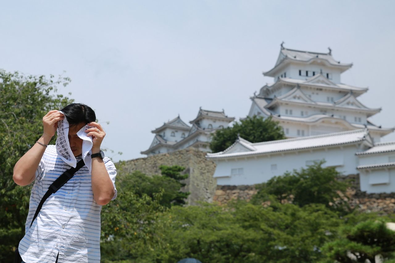 A man attempts to cover his face in Himeji, Japan.