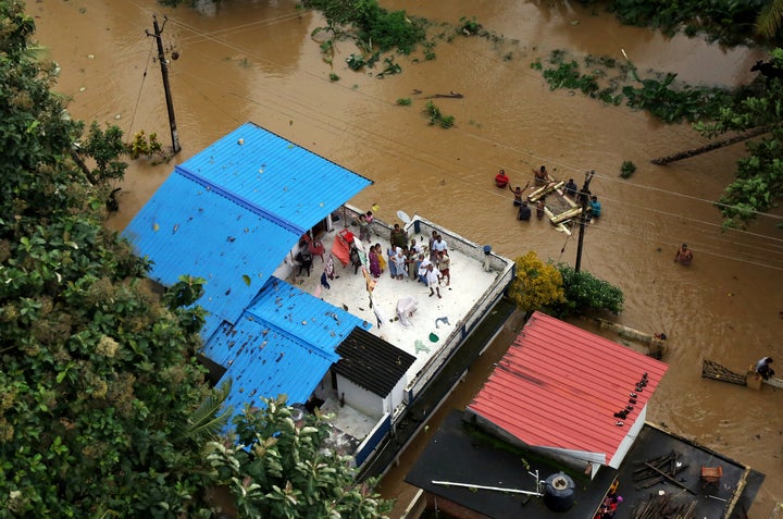 People wait for aid on the roof of their house in a flooded area in Kerala on Aug. 17.