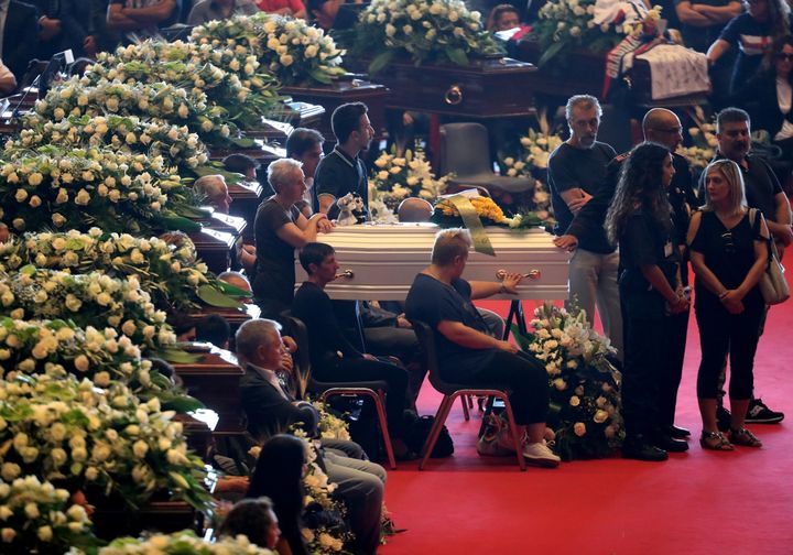 A relative touches the coffin during the state funeral of victims of the Morandi Bridge collapse.