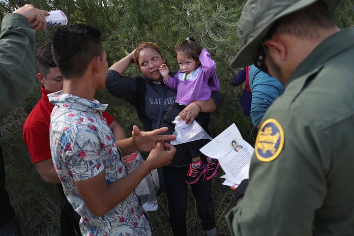 U.S. Border Patrol agents ask a group of Central American asylum-seekers to remove hair bands and wedding rings before taking them into custody on June 12, 2018, near McAllen, Texas. The immigrant families were then sent to a U.S. Customs and Border Protection processing center for possible prosecution under the Trump administration's now-abandoned family separation policy.