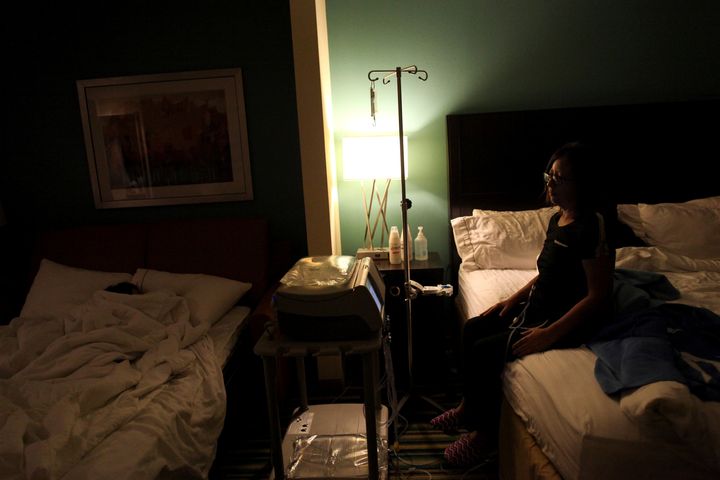 Waleska Rivera, 42, looks at her sleeping 9-year-old son as she undergoes her dialysis treatment in a hotel room in Orlando, Florida, on Dec. 7, 2017.