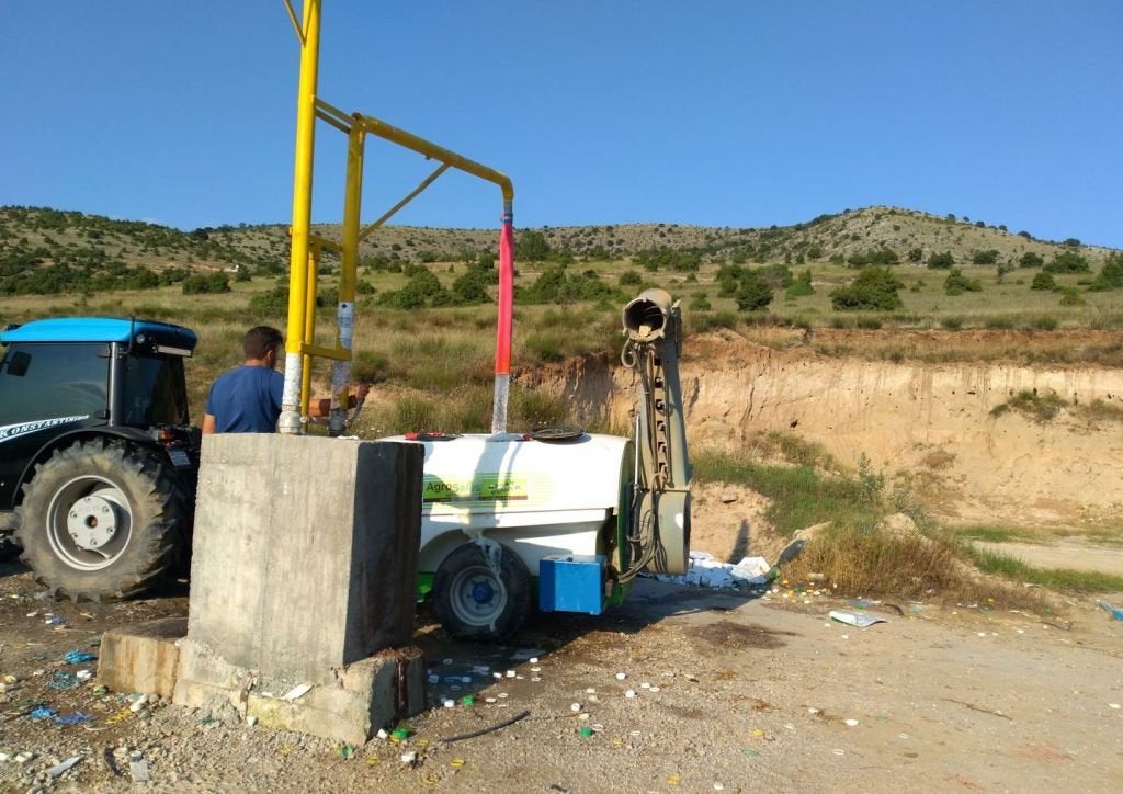 Η εγκατάσταση πλήρωσης του ψεκαστικού με νερό και στο βάθος στο κάθετο πρανές η αποικία των μελισσοφάγων