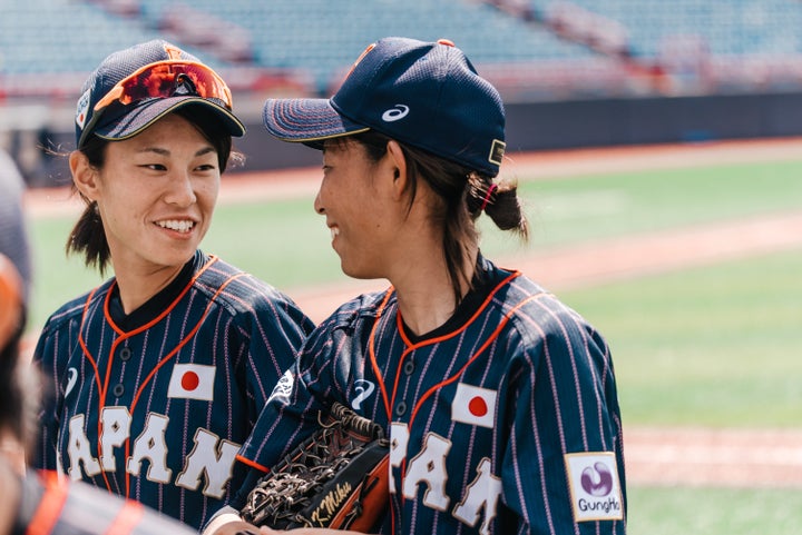 Rina Taniyama (left) and Miku Kitayama (right) talk during the Women's Baseball World Cup as Japan plays against Hong Kong.