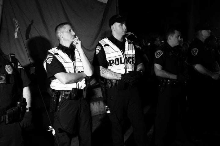 Officer Cole Daniels (center) at the Aug. 20 "Silent Sam" protest with a Three Percenters tattoo visible on his right arm.