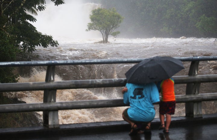 People gather on a bridge to watch the Wailuku River flood waters on the Big Island in Hilo.